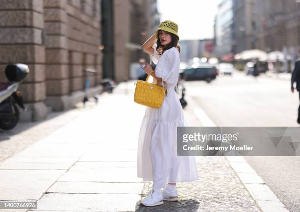 Lena Naumann wearing New Balance x Miu Miu white sneaker, Cecilie Bahnsen white maxi dress, Prada kiwi green bucket hat, Prada yellow bag on May 31,...