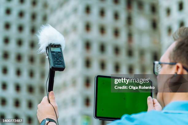 close-up of man in glasses checking sound volume, examining sound noise level by dictaphone and digital tablet against building - risk management stock-fotos und bilder