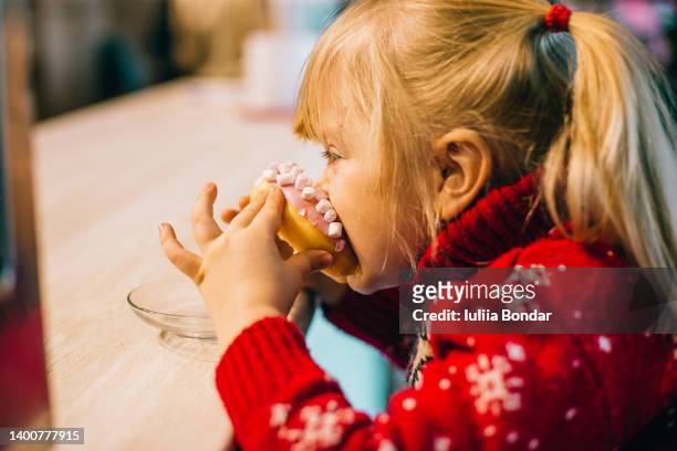little girl eating a donut in a cafe - fat people eating donuts foto e immagini stock
