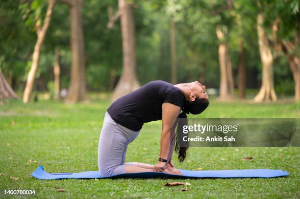 active senior woman doing camel pose or ustrasana exercise at park - leaning back stock pictures, royalty-free photos & images