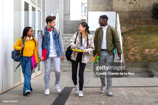 diverse group of college friends walk to class together. multiracial university students talk and have fun outdoors. - 19 to 22 years old stock pictures, royalty-free photos & images