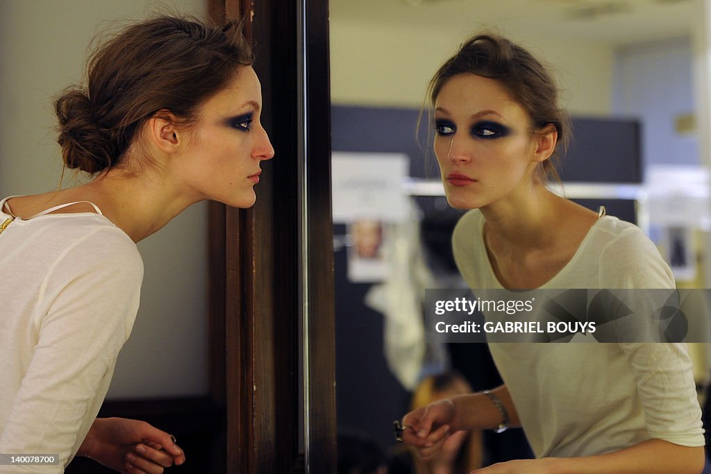 A model looks at her make-up in a mirror