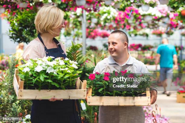 social inclusion - man with down syndrome working in garden center - independece stock pictures, royalty-free photos & images