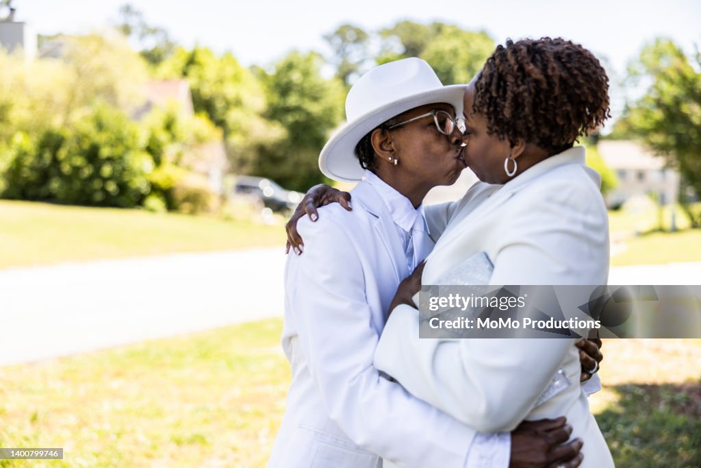 Lesbian Couple Dressed Up In White Suits Kissing Outdoors High Res lesbian-couple-dressed-up-in-white-suits-kissing-outdoors-high-res