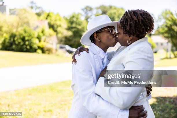 lesbian couple dressed up in white suits kissing outdoors - black lesbians kiss stock pictures, royalty-free photos & images