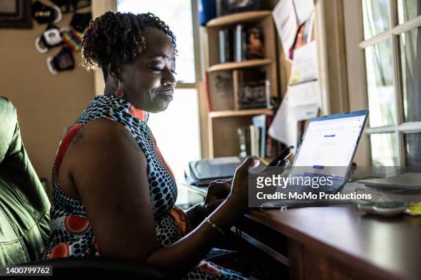 woman using laptop and smartphone in home office - black population stock pictures, royalty-free photos & images