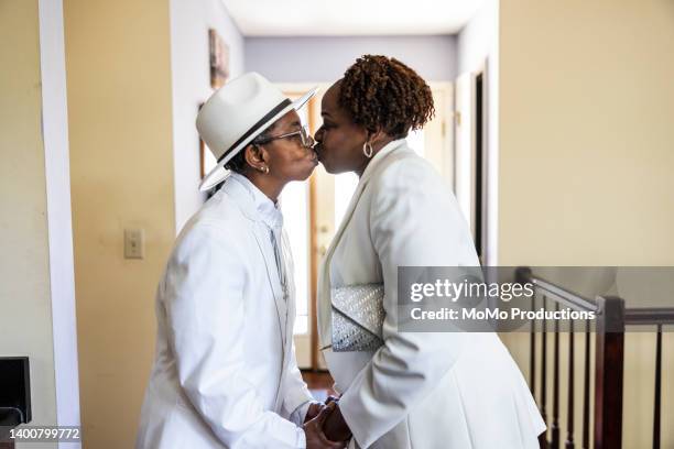 lesbian couple dressed up in white suits kissing indoors - black lesbians kiss stock pictures, royalty-free photos & images