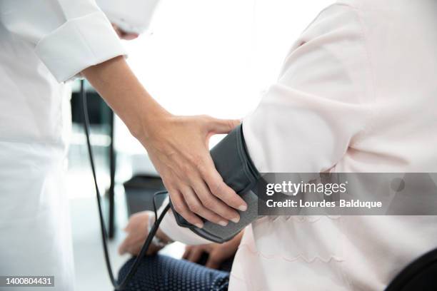 measuring the pressure of senior woman - bluthochdruck stock-fotos und bilder