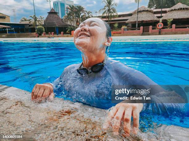 asian chinese woman float from water surface with satisfied and happy look - older woman wet hair stock pictures, royalty-free photos & images