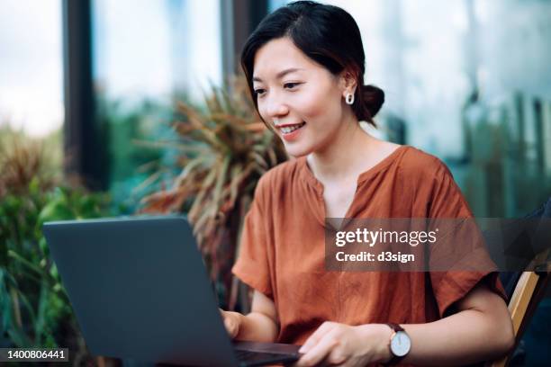 beautiful young asian woman sitting on deck chair in the balcony, managing banking and finance with online banking on laptop. handling financial bill payment at easy access. lifestyle and technology. convenience and easy banking with technology - computer work life balance stockfoto's en -beelden