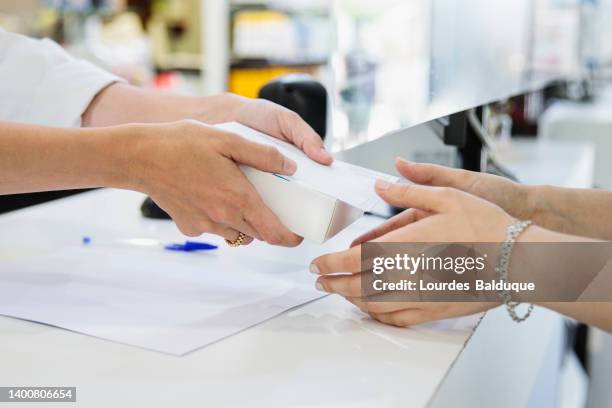 pharmacist handing a box of medicine to a customer in a pharmacy - pharmacy stock pictures, royalty-free photos & images