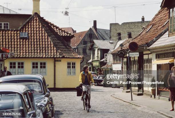 Cyclist cycles past Hans Christian Andersen House, a yellow house considered to be the birthplace of the Danish author, on the corner of Hans Jensens...