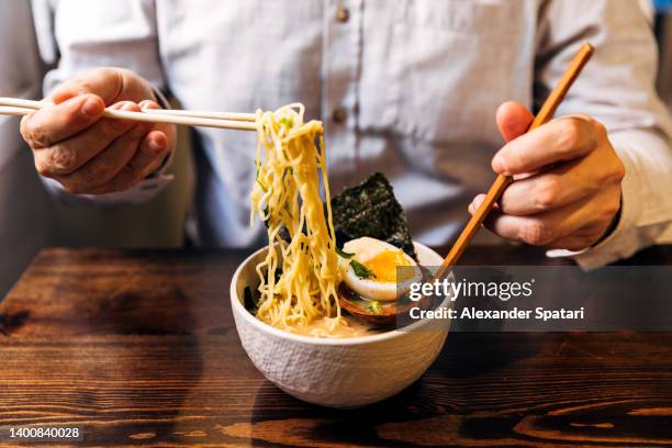close-up of man eating ramen soup with noodles, pork and egg - 皿　和 ストックフォトと画像