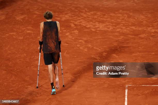 Alexander Zverev of Germany leaves the court on crutches after being forced to retire following an injury against Rafael Nadal of Spain during the...