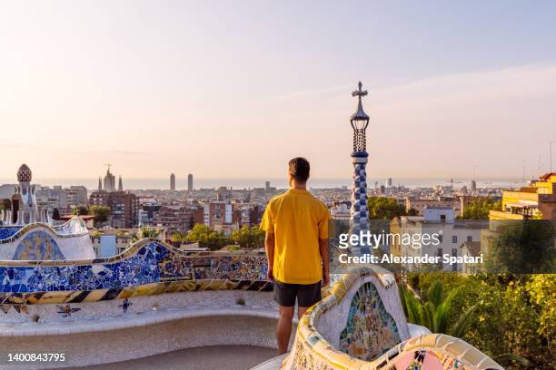 rear view of a man in yellow shirt looking at barcelona skyline from above, spain - barcelona spain stock pictures, royalty-free photos & images