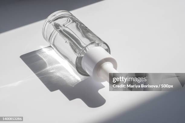 a white transparent bottle with serum in the rays of the sun - solid perfume stock pictures, royalty-free photos & images