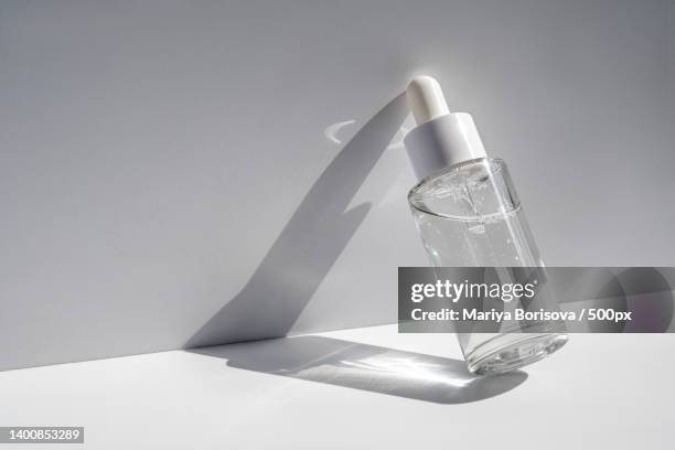 a white transparent bottle with serum in the rays of the sun - solid perfume stock pictures, royalty-free photos & images