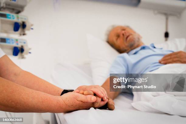 wife holding husband's hand at the hospital - hospital bracelet stock pictures, royalty-free photos & images