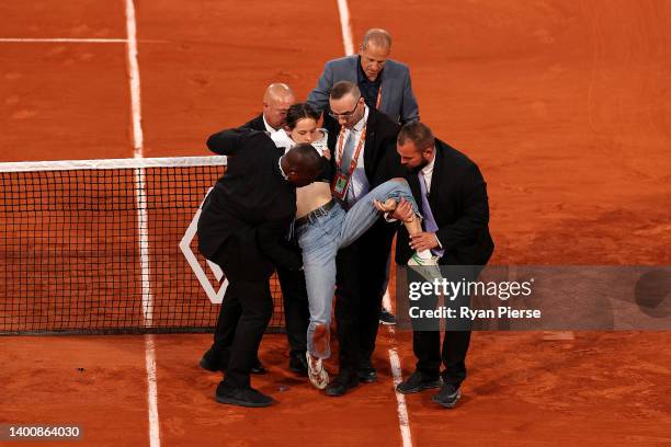 Protester is carried off the court after tying themselves to the net during the Men's Singles Semi Final match between Marin Cilic of Croatia and...