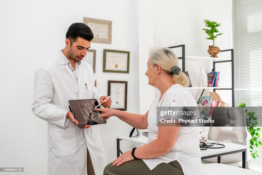 Plan d’un jeune médecin utilisant une tablette numérique lors d’une consultation avec une femme âgée