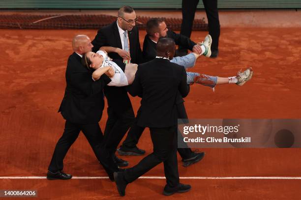 Protester is carried off the court after tying themselves to the net during the Men's Singles Semi Final match between Marin Cilic of Croatia and...