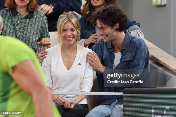 Sienna Miller and Oli Green watch Rafael Nadal of Spain during the Men's Singles Semi Final match on Day 13 of The 2022 French Open at Roland Garros...