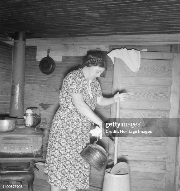 Wife of tobacco sharecropper cleaning butter churn. Person County, North Carolina. Artist Dorothea Lange.