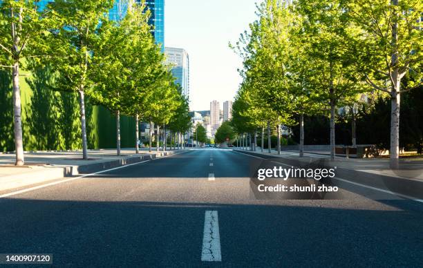 city street under the shade of trees - städtischer verkehrsweg stock-fotos und bilder
