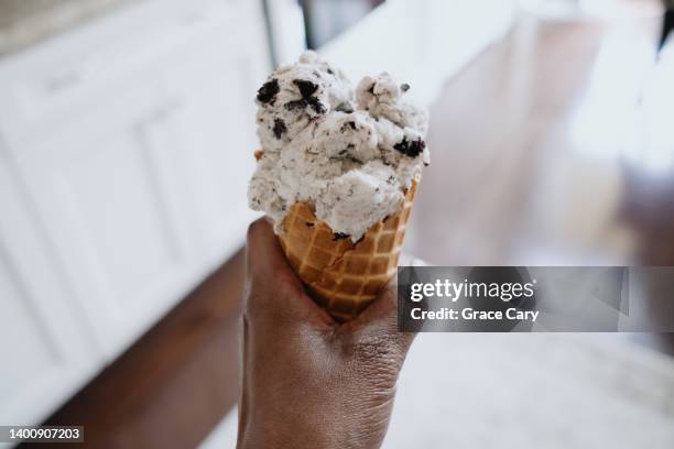 woman holds cookies and cream ice cream on waffle cone - cookies and cream ice cream stock pictures, royalty-free photos & images