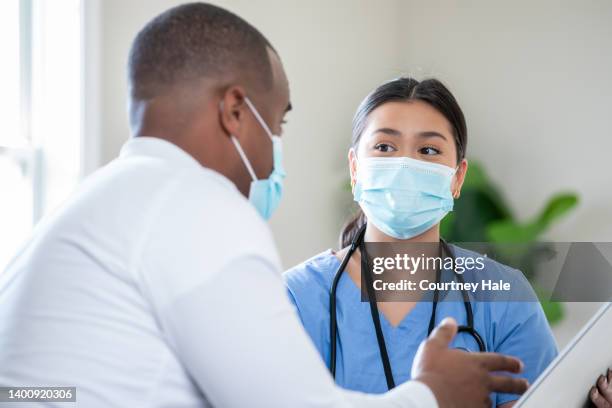 doctor and nurse discuss medical chart together - social worker mask stock pictures, royalty-free photos & images