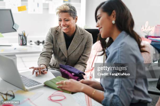 les femmes asiatiques multiraciales travaillent ensemble à l’aide d’un ordinateur portable dans un intérieur de bureau de design de mode moderne et créatif - industrie de la mode photos et images de collection