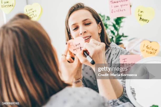 woman writing affirmations on a sticker near the mirror. - health motivational quotes stock pictures, royalty-free photos & images
