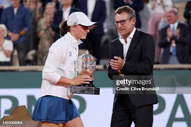 Iga Swiatek of Poland is presented with the winners trophy by Mats Wilander after winning against Coco Gauff of The United States during the Women’s...