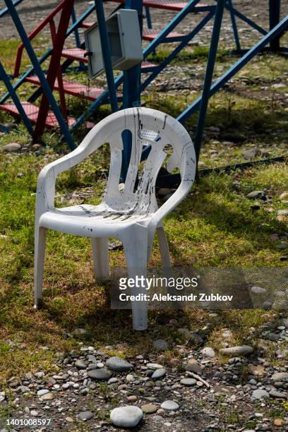 an old dirty white plastic chair with a broken back. the concept of environmental pollution, excessive consumerism. - abandoned crack house stock pictures, royalty-free photos & images