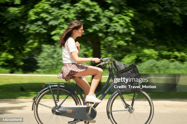 woman cycling in urban park on a summer day, vondelpark, amsterdam - vondelpark stockfoto's en -beelden