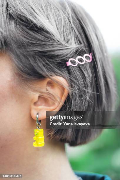 senior woman with grey hair, hairpin on temple and gummy bear earring - earring stud stock pictures, royalty-free photos & images