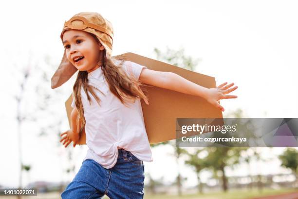 petite fille heureuse avec des ailes jouant dehors sur la piste de course - aile de déguisement photos et images de collection