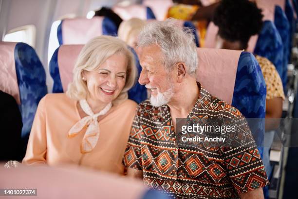 happy senior couple smiling during flight - couple airplane stock pictures, royalty-free photos & images