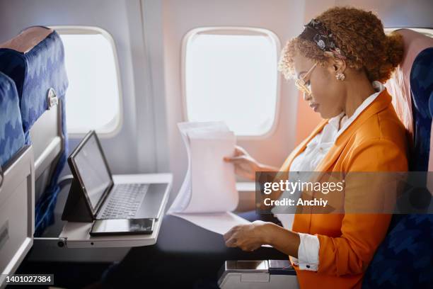 mujer de negocios leyendo documentos y trabajando en tableta digital durante el vuelo - aircraft wifi fotografías e imágenes de stock