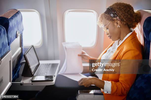 businesswoman reading documents  and working on digital tablet during flight - business air travel stock pictures, royalty-free photos & images