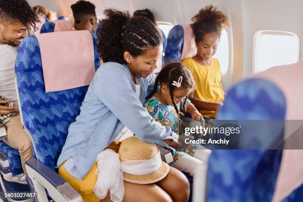 the mother helps the child to fasten seat belt on the plane - aisle seat airline stock pictures, royalty-free photos & images