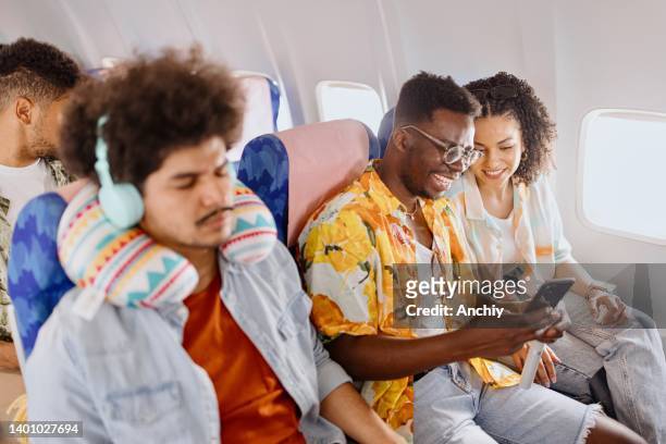 couple watch something on a smartphone while traveling with plane - couple airplane stockfoto's en -beelden