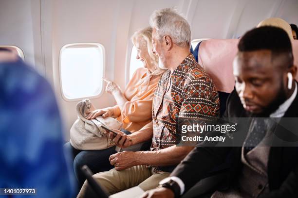 senior couple sitting in airplane looking out of window - passenger stock pictures, royalty-free photos & images
