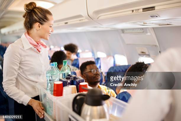 azafatas que sirven comida y bebidas al cliente en el avión durante el vuelo - tripulación fotografías e imágenes de stock