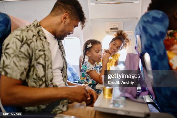 family having fun during flight. eating food and dinking juice and water - airport crew stock pictures, royalty-free photos & images