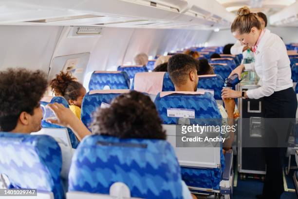stewardesses serving food and drinks to customer on the airplane during flight - airline service stock pictures, royalty-free photos & images