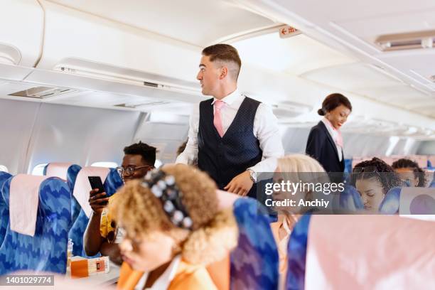 auxiliar de vuelo masculino que revisa a los pasajeros antes de despegar - window seat fotografías e imágenes de stock