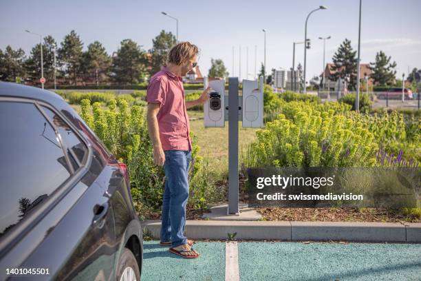 man charging electric car - toyota stock pictures, royalty-free photos & images