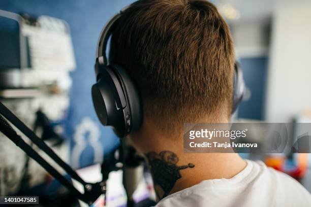 rear view on male podcaster in headphones making audio podcast from her home studio - streaming music stock pictures, royalty-free photos & images