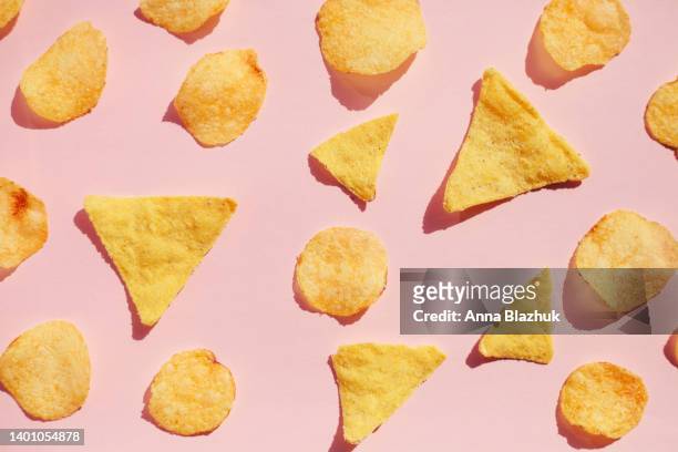 potato chips pattern over pink background, hard light with shadows. unhealthy junk food concept. - bag of potato chips stockfoto's en -beelden